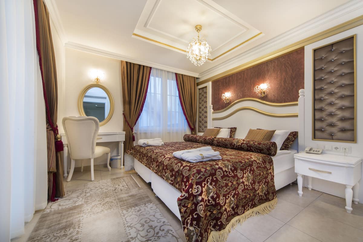 A hotel bedroom with a large bed, a desk, and a chair.