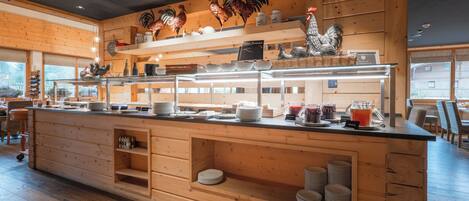 A wooden interior with a buffet counter, wooden shelves, and decorative roosters.
