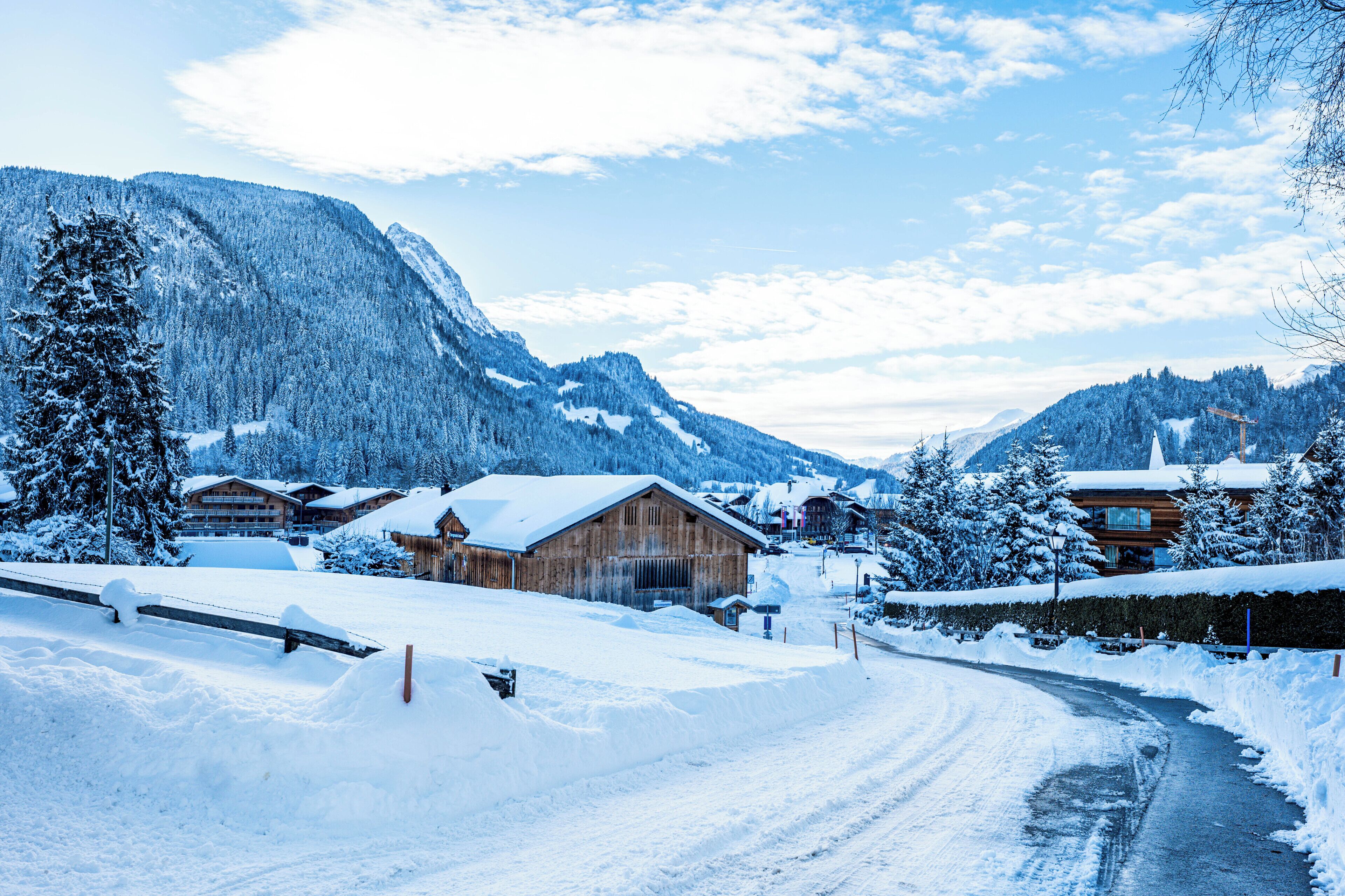 A snow-covered mountain village with wooden buildings and a winding road.