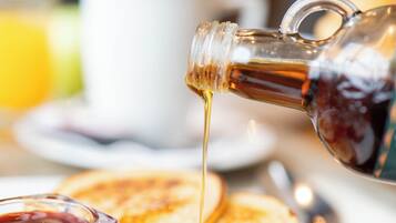 Desayuno con tortitas, jarabe y una taza de café.