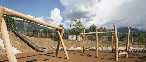 Un parque infantil con columpios, un tobogán y estructuras para escalar.