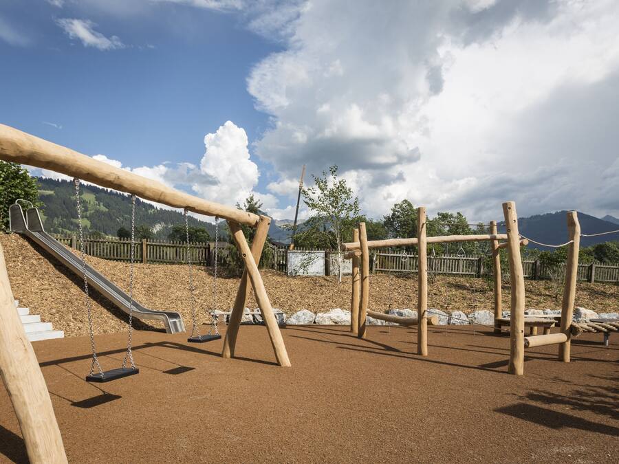 Un parque infantil con columpios, un tobogán y estructuras para escalar.