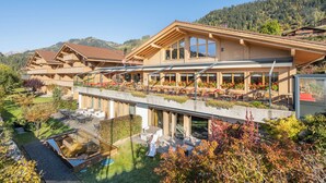 A multi-story hotel with outdoor seating and a view of the surrounding mountains. - Hotel Spitzhorn (Saanen)