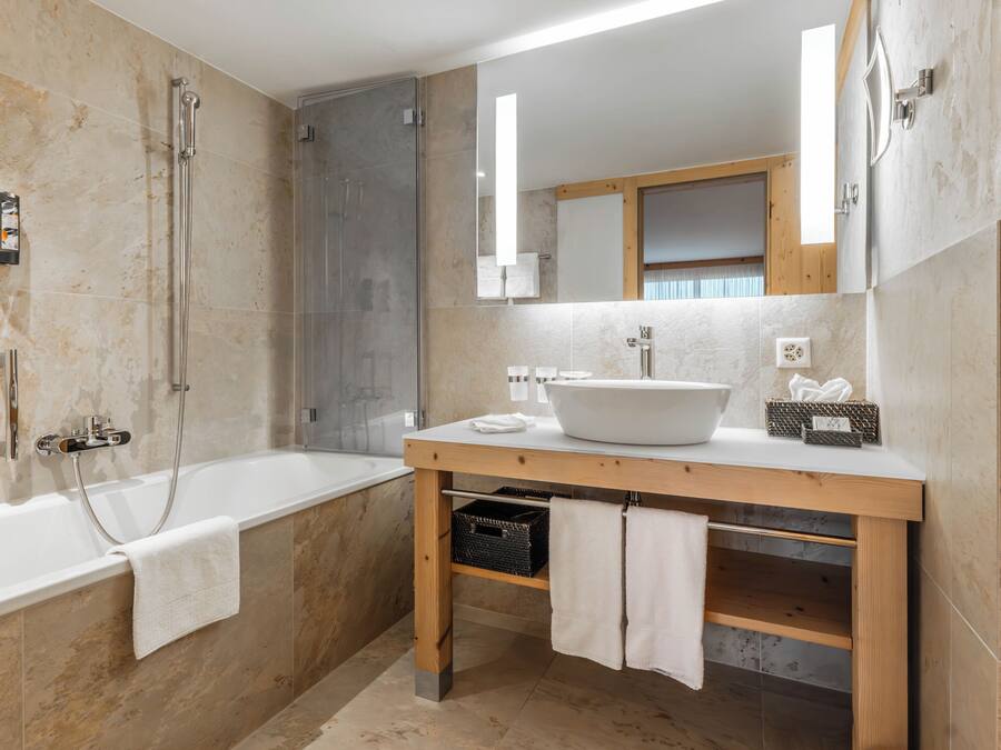 Un bany modern amb una banyera, un tocador de fusta amb un lavabo gran i un mirall sobre el tocador.