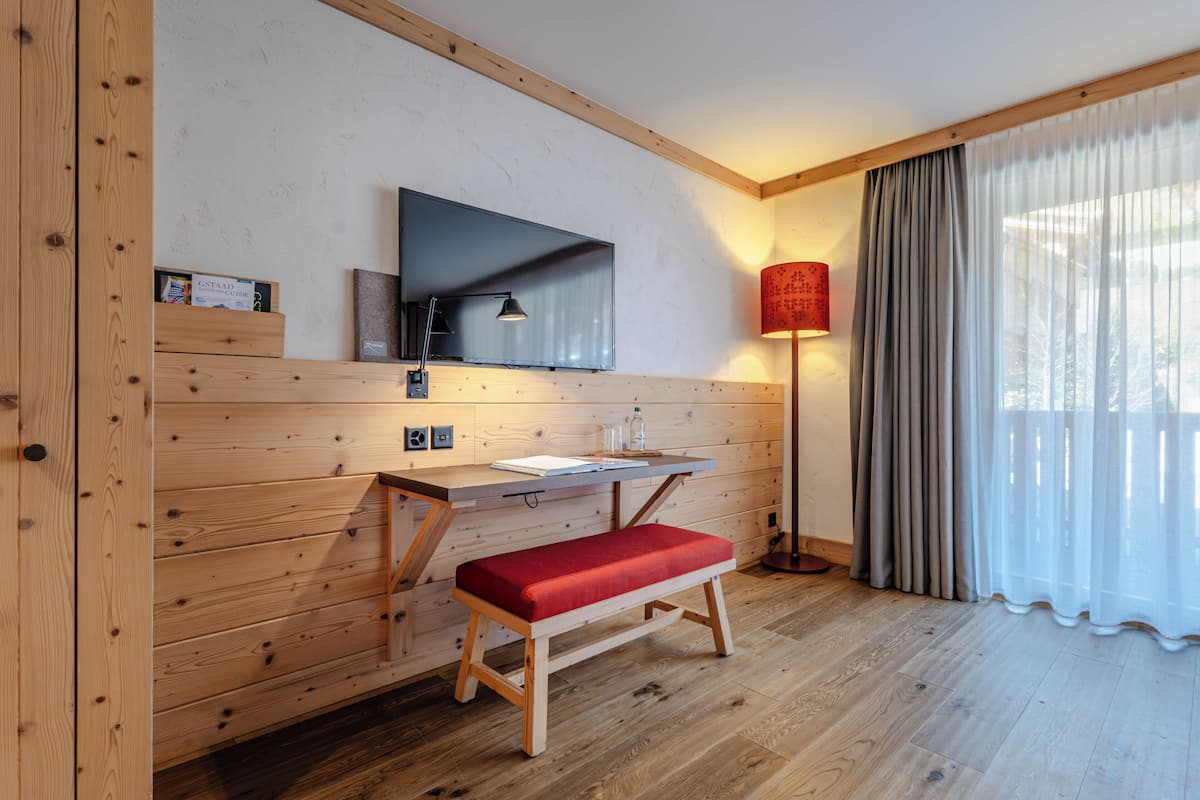 A wooden-paneled room with a desk, bench, TV, lamp, and curtains.