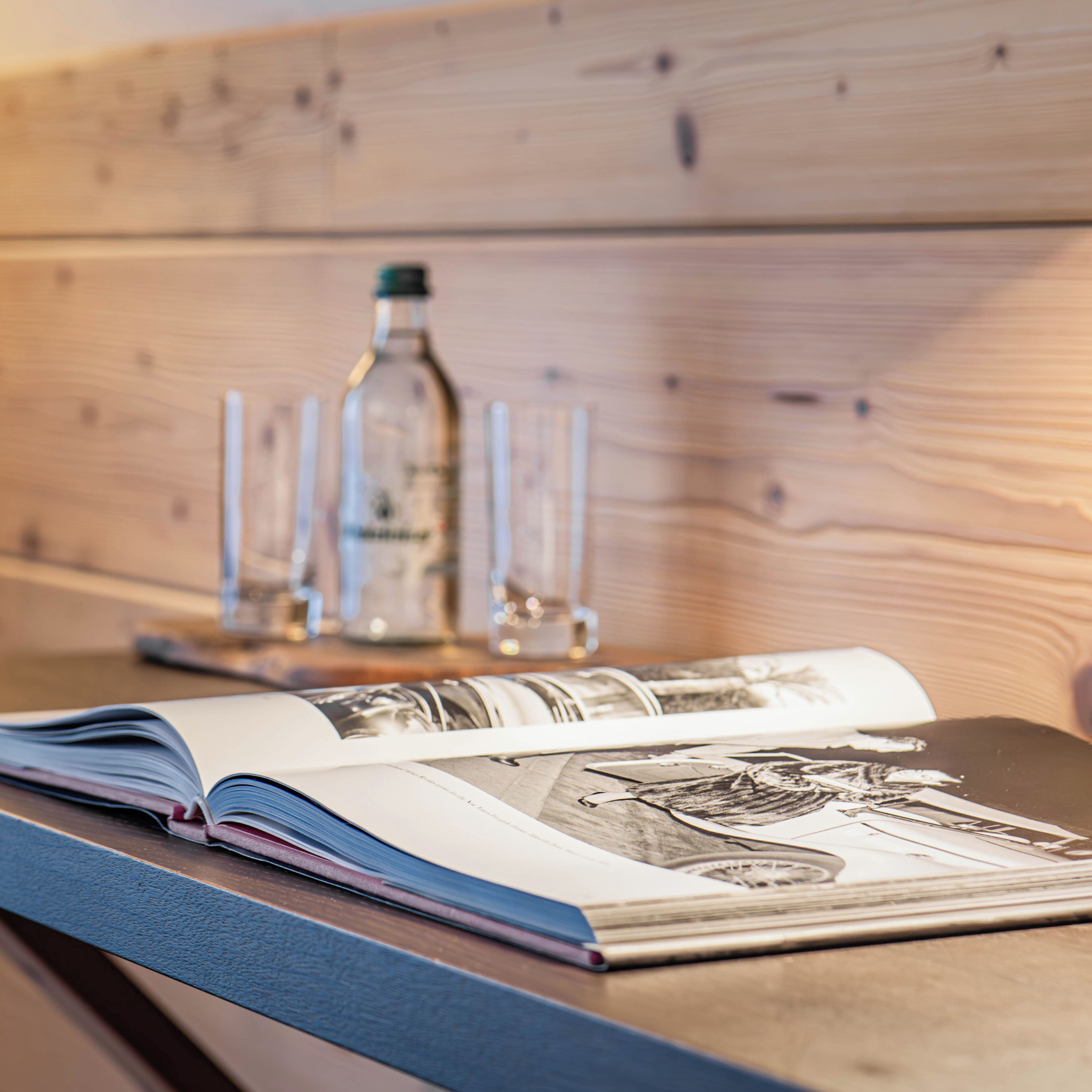 A wooden table with a magazine and a bottle of water.