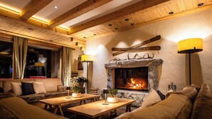 A cozy interior with a stone fireplace, wooden beams, and comfortable seating. - Hotel Spitzhorn (Saanen)