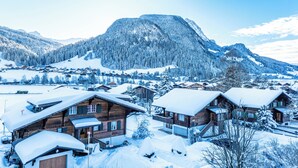 A snowy mountain village with wooden cabins and a prominent mountain in the background. - Hotel Spitzhorn (Saanen)