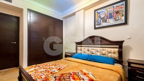 A bedroom with a large wardrobe, a bed with a patterned blanket, a nightstand, and a framed picture on the wall. - Résidence Mirador Majorelle (Marrakech)