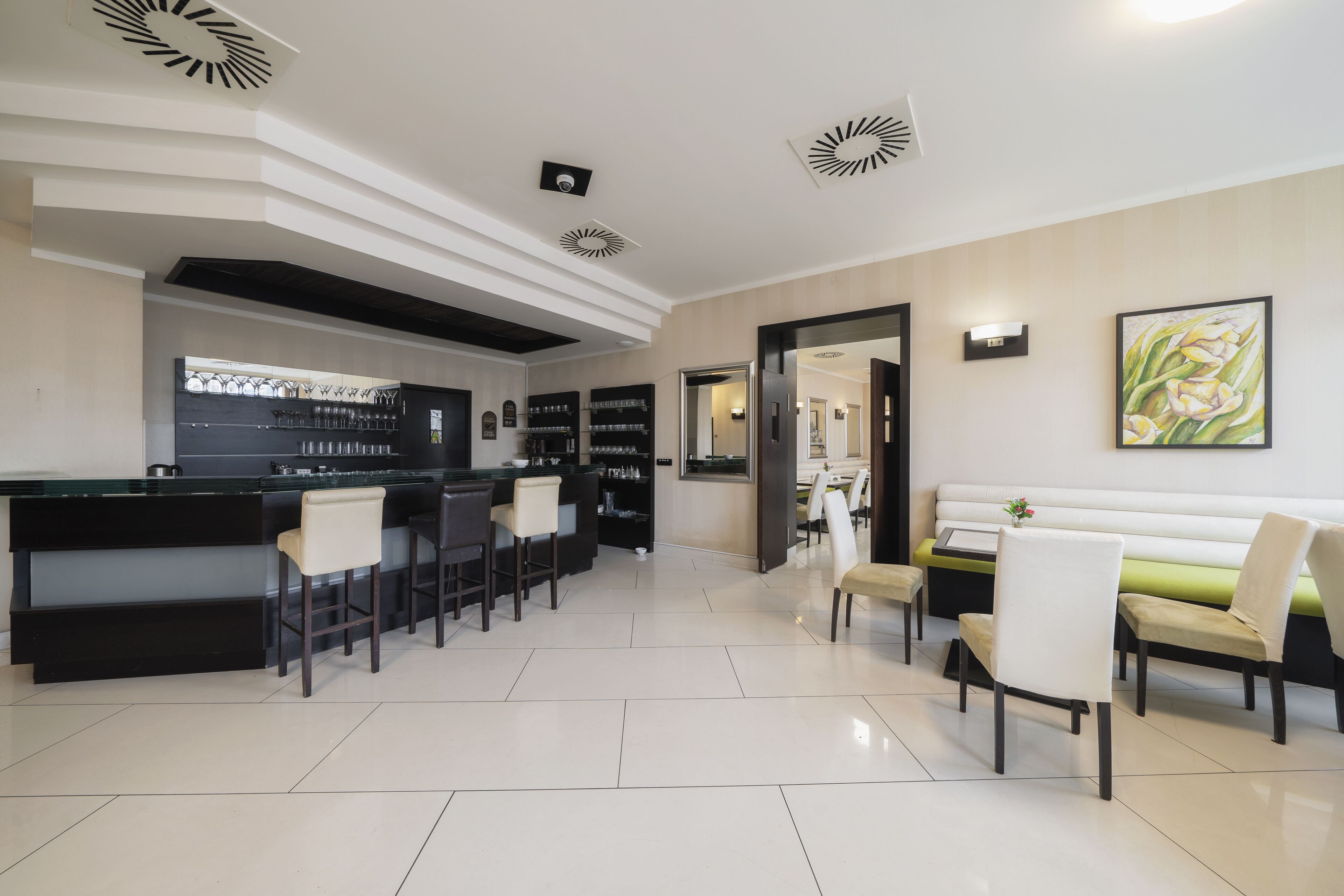 Un hall d’hôtel moderne doté d’un bar, de coins salon et d’un comptoir d’accueil.