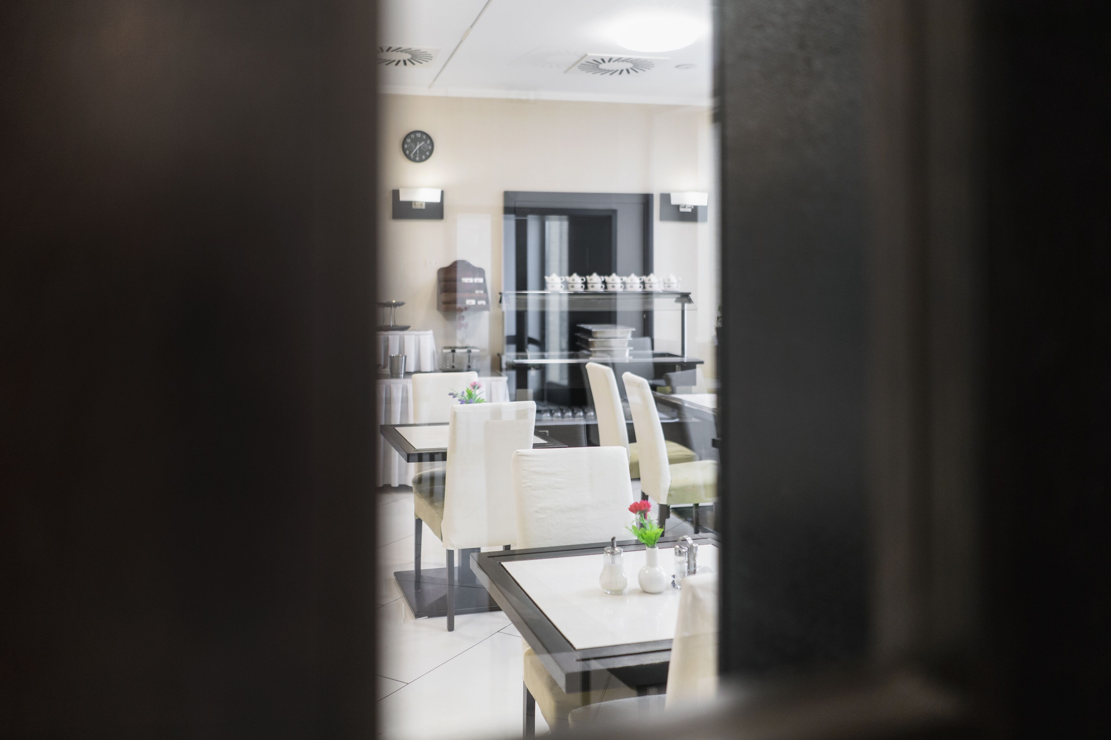 Un espace repas avec des tables et des chaises, une horloge au mur et un comptoir où sont exposés divers articles.
