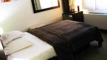 Quarto com cama, mesa de cabeceira, espelho, luminária e janela com cortinas.