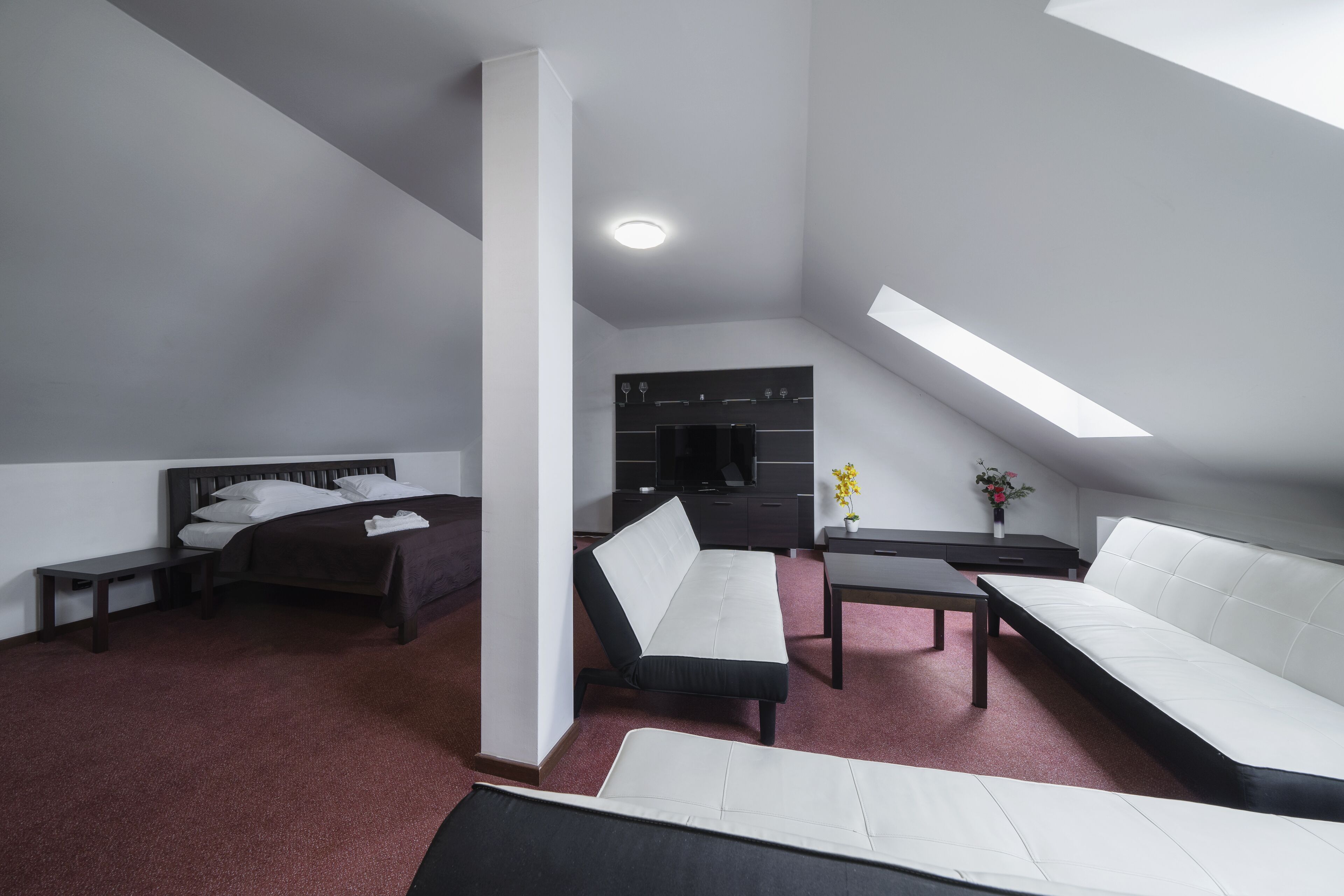 A modern, well-lit room with a bed, a sofa, and a desk.