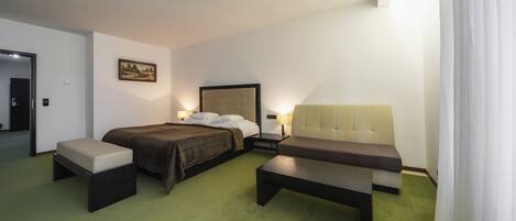 A hotel room with a bed, two bedside tables, a bench, and a painting on the wall.
