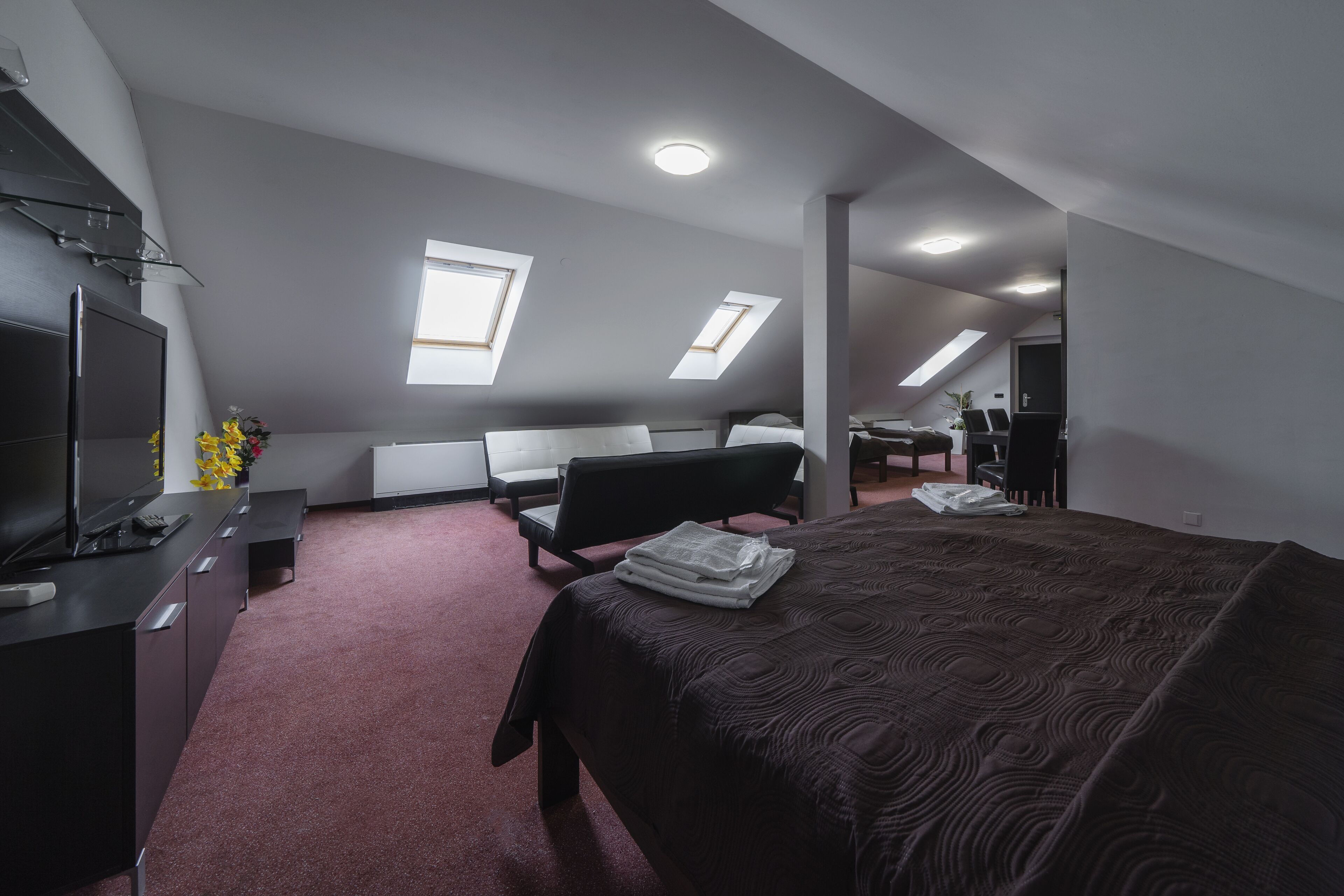 A modern, compact room with a bed, desk, and seating area.