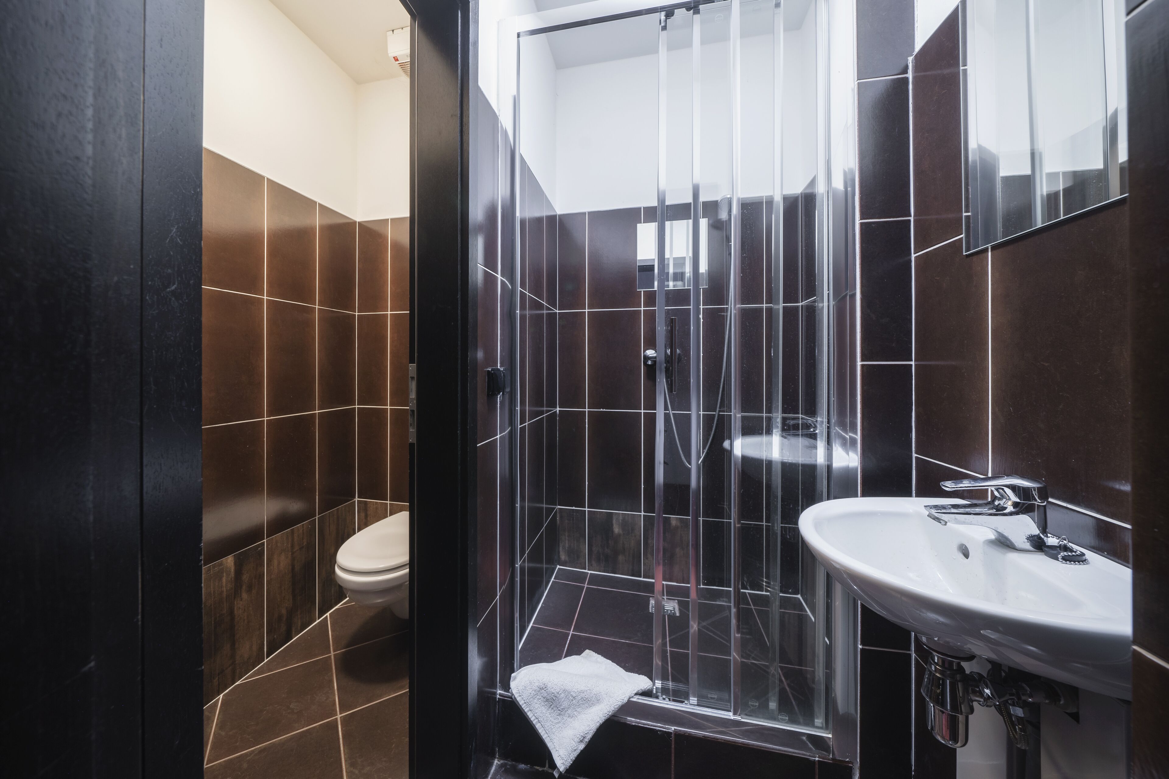 Un baño moderno con cabina de ducha de vidrio, un lavamanos blanco y un inodoro.