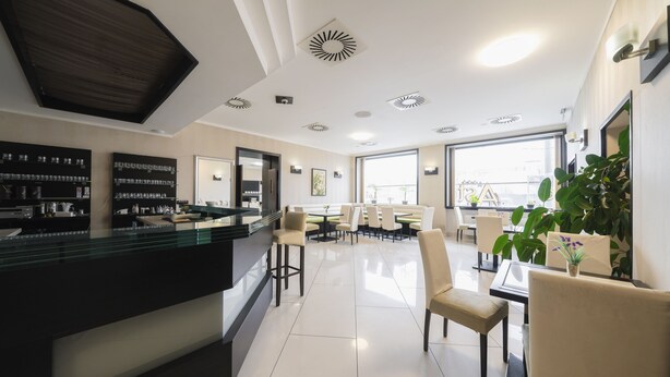 A modern hotel lobby with a reception desk, seating area, and large windows. - Astory Hotel (Plzen)