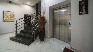 A modern interior with a staircase, elevator, and a large potted plant. - Astory Hotel (Plzen)