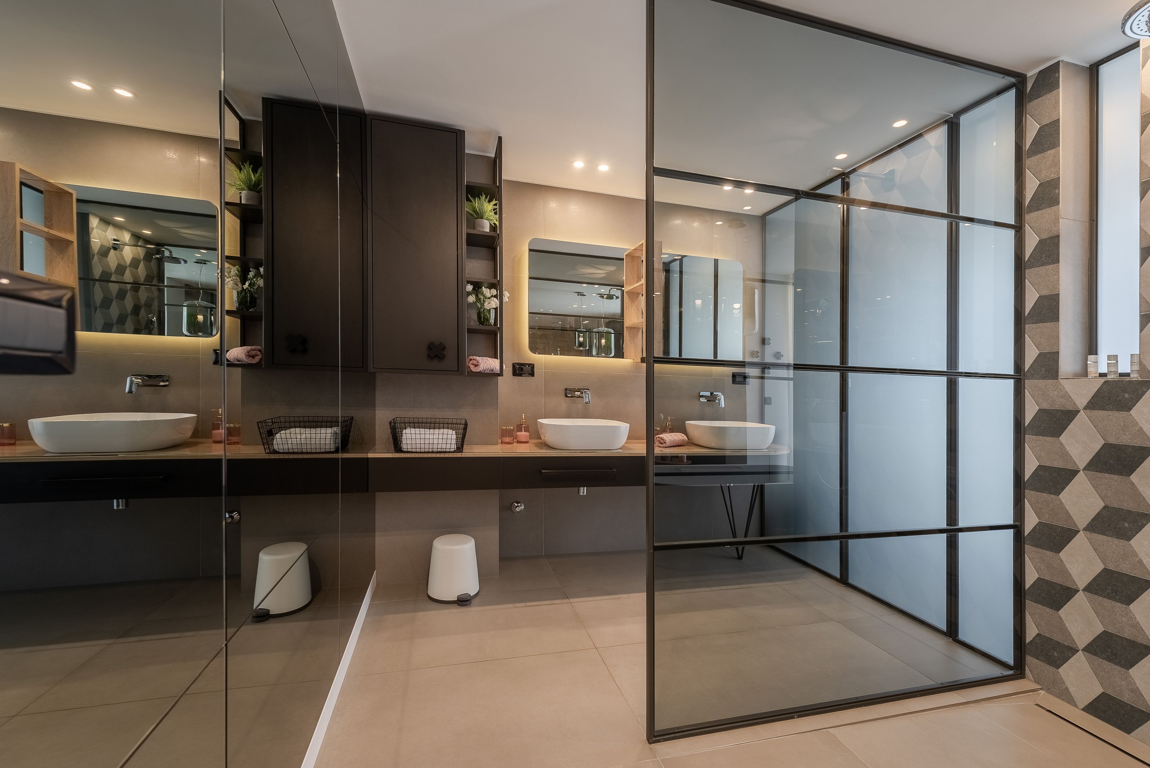 A modern bathroom with two sinks, a glass shower enclosure, and a large mirror.