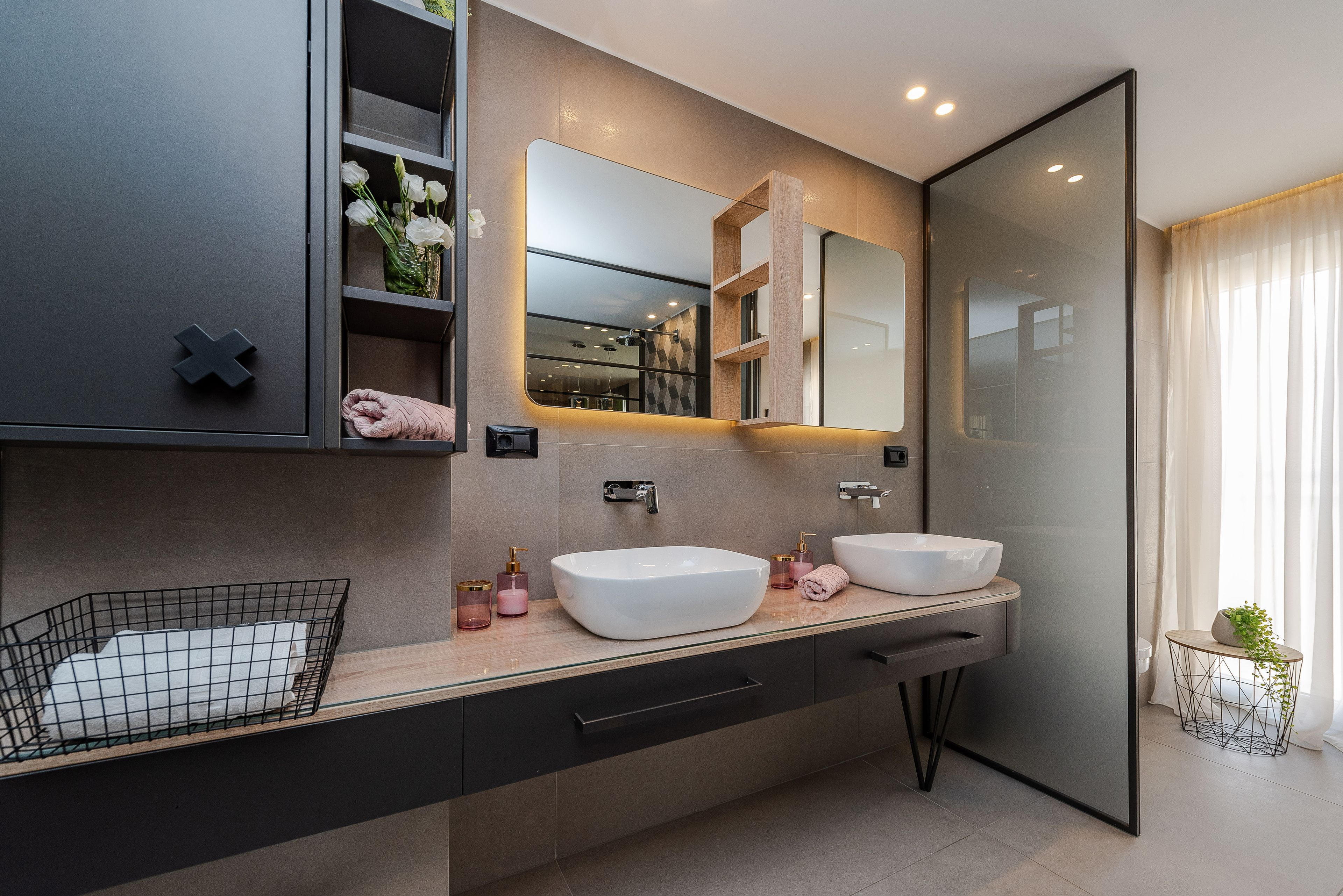 Une salle de bain moderne avec deux lavabos, un grand miroir et un porte-serviettes.