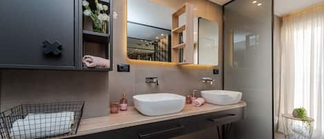 Un bagno moderno con due lavandini, uno specchio grande e un portasciugamani.