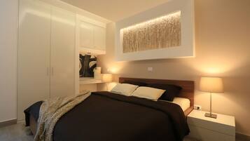 A bedroom with a bed, nightstands, a wall-mounted artwork, and a wardrobe.
