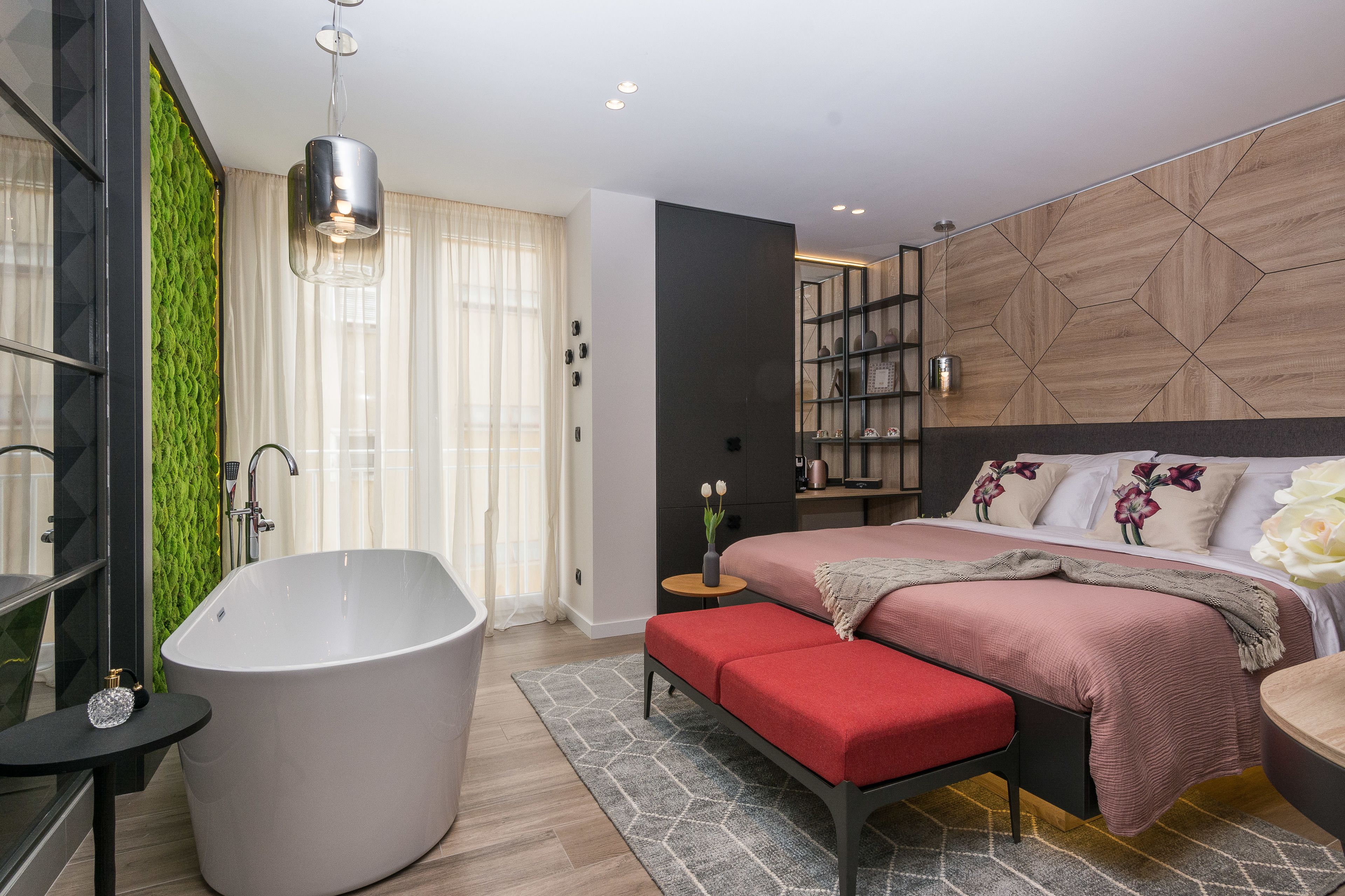 Ein modernes Schlafzimmer mit einer großen Badewanne, einem Bett mit einer roten Bank und einer grünen Akzentwand.