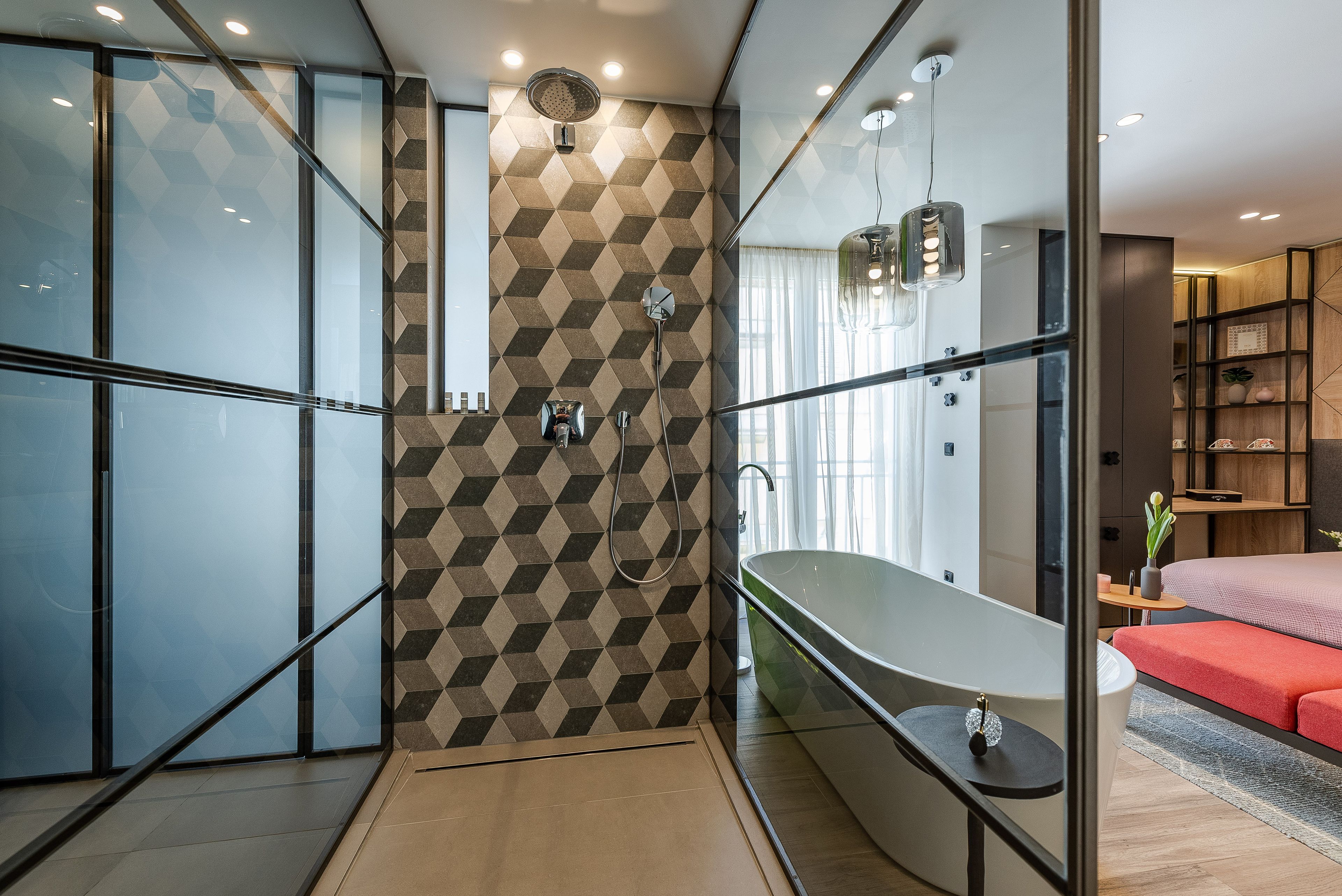 A modern bathroom with a geometric patterned wall, a freestanding bathtub, and a glass shower enclosure.