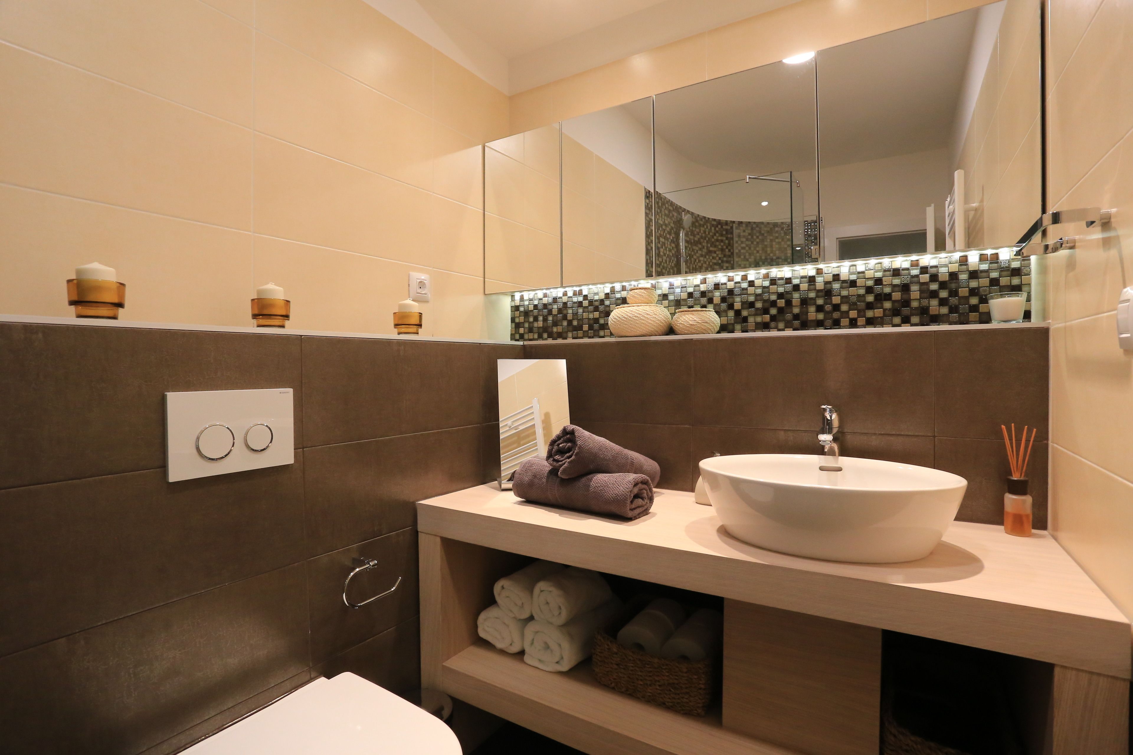 A modern bathroom with a large mirror, a white sink, and a towel rack.