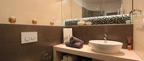 A modern bathroom with a large mirror, a white sink, and a towel rack.