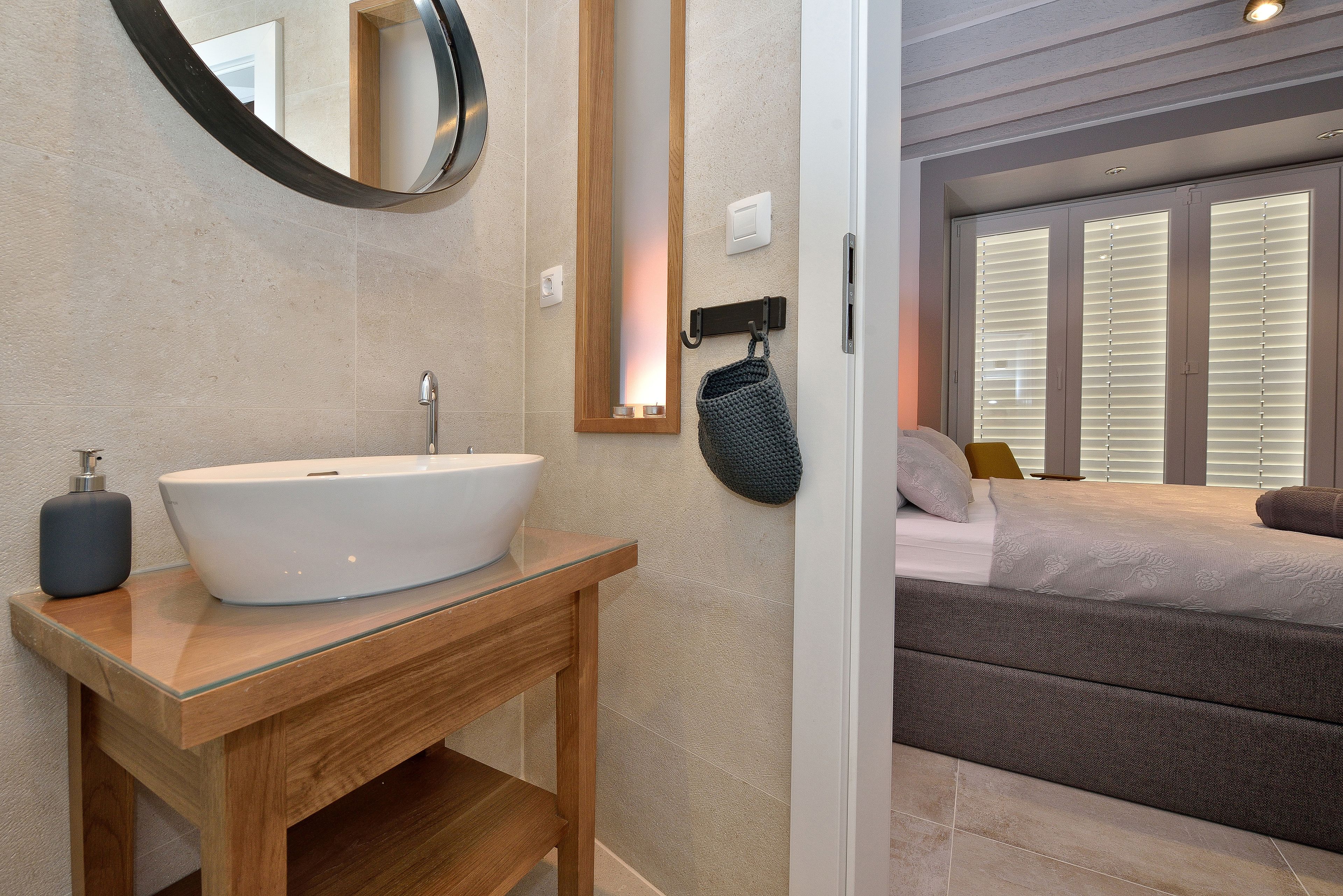 Un baño moderno con un lavamanos ovalado grande, tocador de madera y un espejo.