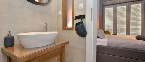 A modern bathroom with a large oval sink, wooden vanity, and a mirror.