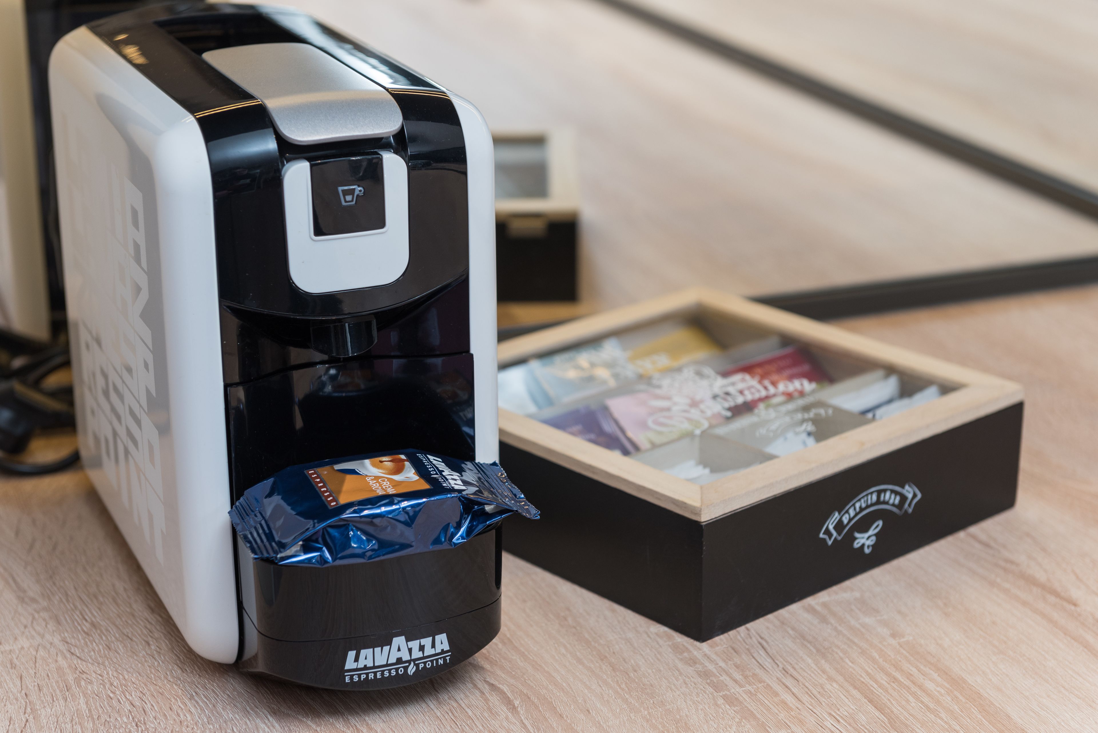 A coffee machine with a cup of coffee and a box of coffee pods.