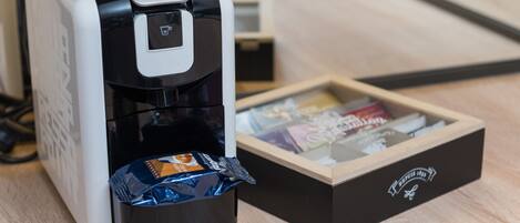 Una cafetera con una taza de café y una caja de cápsulas de café.