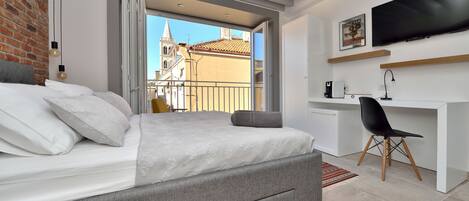 Un dormitorio moderno con una cama, un escritorio y una televisión.
