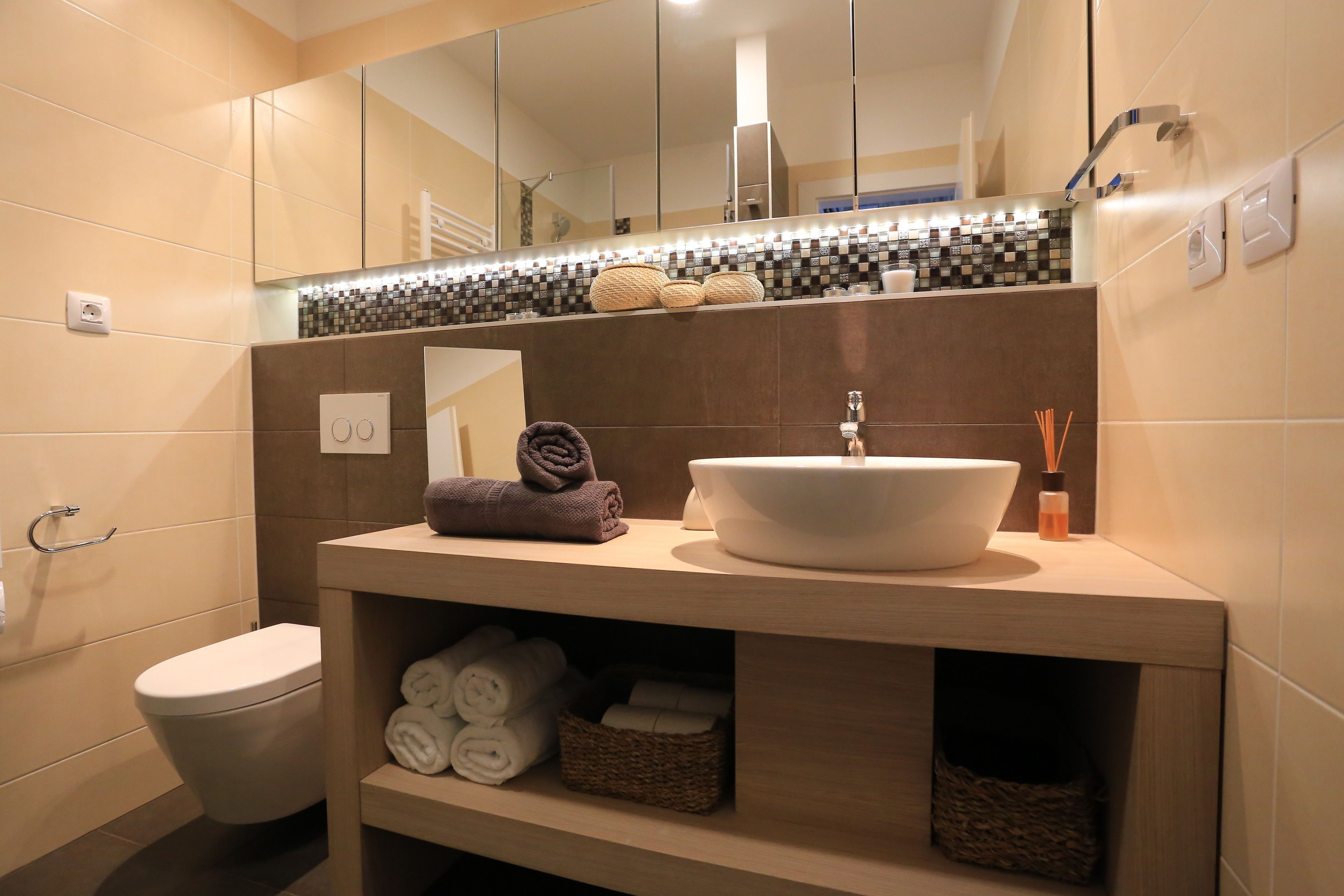 A modern bathroom with a large mirror, a white sink, and neatly folded towels on the vanity.