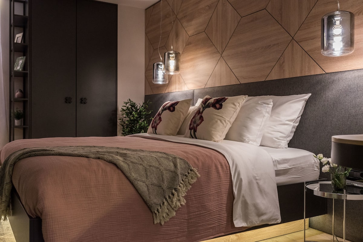 A modern bedroom with a bed, a wardrobe, and a nightstand.