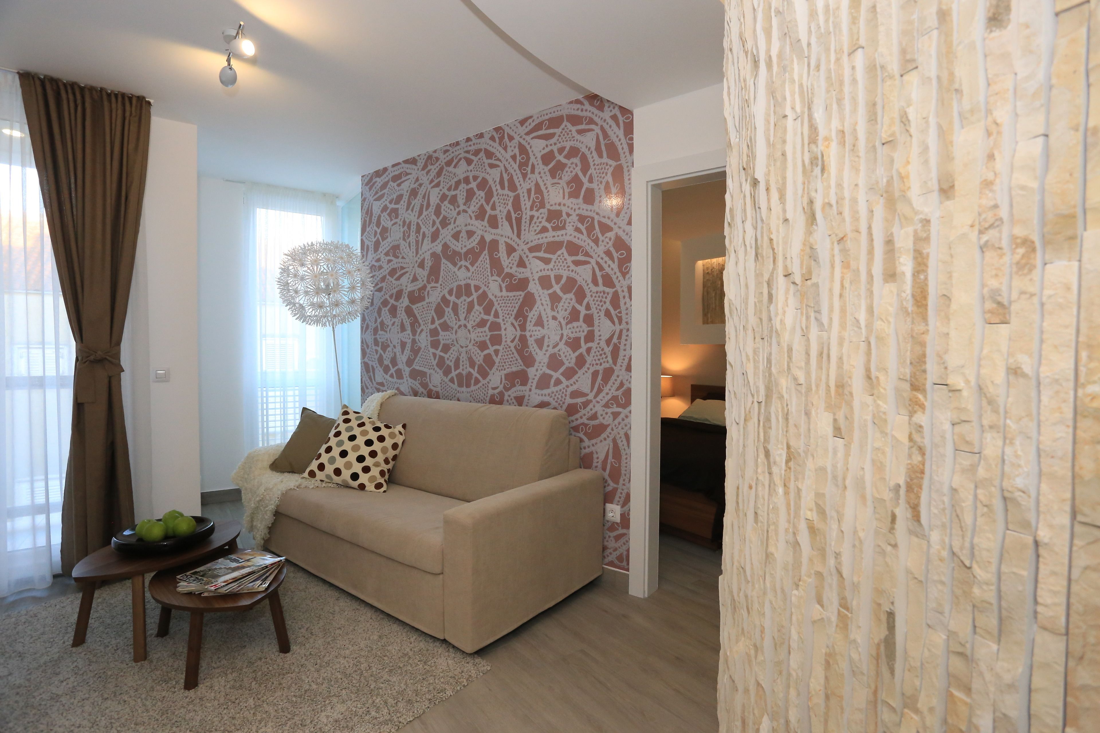 Una sala de estar con un sofá beige, una mesita de centro con revistas y un adornado en la pared.