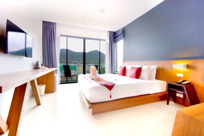 A modern hotel room with a large bed, a desk, a flat-screen TV, and a city view. - Phoenix Grand Hotel (Patong)