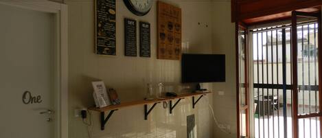 A room with a wall clock, a menu board, a flat-screen TV, and a door labeled "One".