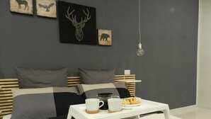 A modern bedroom with a bed, a white coffee table with a cup and pastries, and wall art depicting animals. - Mola Rooms (Naples)