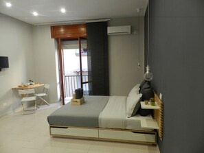 Quarto moderno com cama, mesa de cabeceira e escrivaninha com cadeiras.