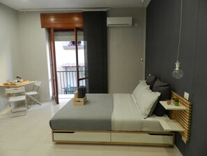 Um quarto moderno com uma cama, mesa de cabeceira e uma pequena escrivaninha com cadeiras.