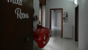 A hallway with a red car parked against the wall, a door labeled "Mola Rooms," and a radiator on the wall. - Mola Rooms (Naples)