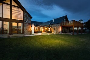 A stone building with a wooden deck and a large glass window. - The Steading (Dornoch)