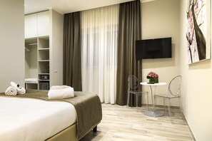 A hotel room with a bed, a desk, a chair, a TV, and a wardrobe. - Aeterno Eco Guest House (Rome)