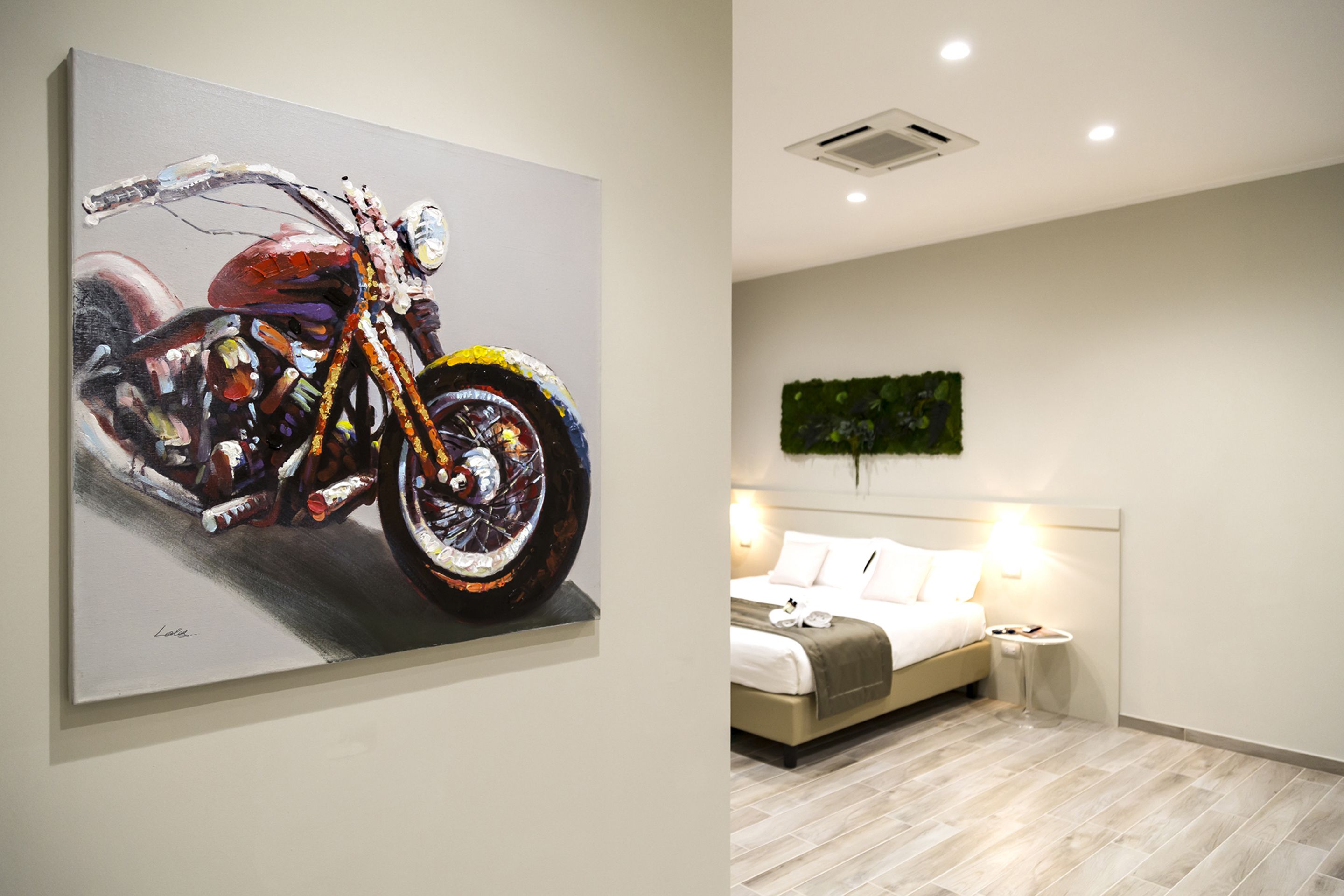 Ein Zimmer mit einem Bett, einem Nachttisch und einem Bild von einem Motorrad.