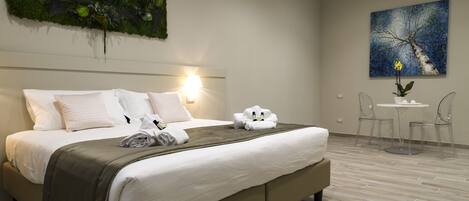 Una habitación de hotel moderna con una cama grande, una mesita redonda con sillas y una obra de arte colgada en la pared.