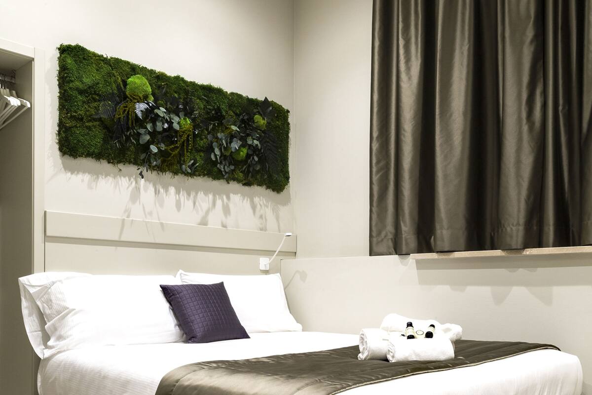 Une chambre moderne avec un lit, une décoration murale verte et une fenêtre avec des rideaux.