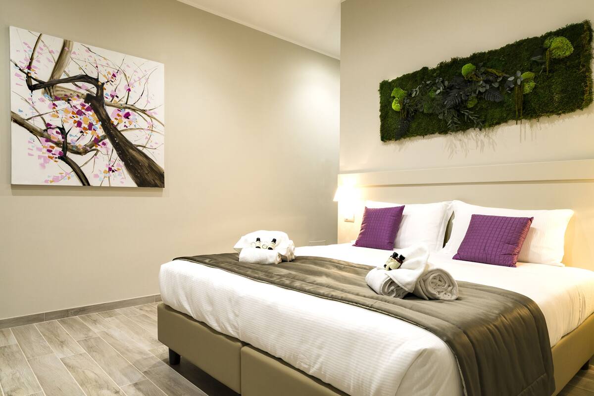 Une chambre d’hôtel avec un lit, des oreillers, une couverture et une œuvre d’art murale.